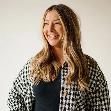 A woman with black and white checkered jacket, showcasing her hair color.