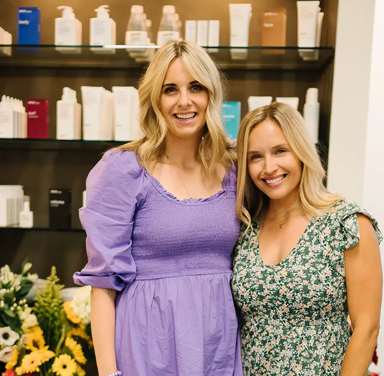 Two women in front of a shelf of beauty products at Salon M + Suites. Two women in front of a shelf of beauty products at Salon M + Suites.