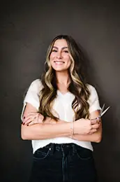 A woman with long hair wearing a white shirt, holding scissors. A woman with long hair wearing a white shirt, holding scissors.