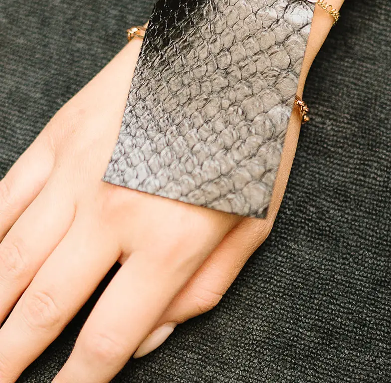 A woman's hand holds a black snake skin bracelet at Salon M + Suites. A woman's hand holds a black snake skin bracelet at Salon M + Suites.