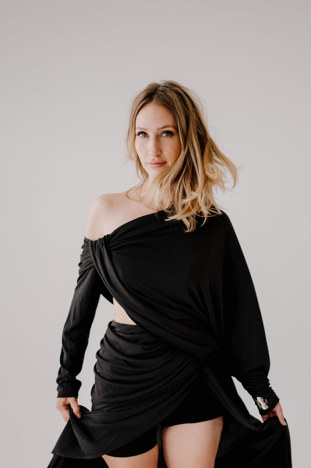A woman in a black and grey sweater, seated on a chair, possibly undergoing haircuts or blowouts.